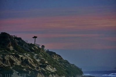 Low angle view of person standing on cliff against sky