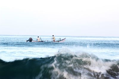 People in sea against clear sky