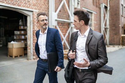 Two businessmen walking and talking at an old brick building