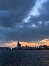 City at waterfront against cloudy sky