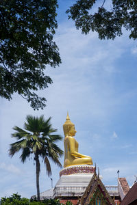 Low angle view of statue amidst trees against sky