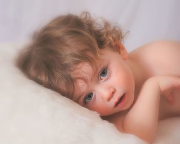 Close-up portrait of baby boy lying down on bed at home