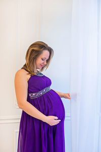 Pregnant woman standing by curtain