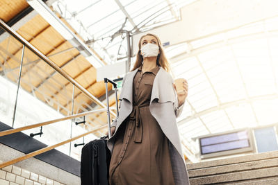 Low angle view of woman wearing mask moving down on steps