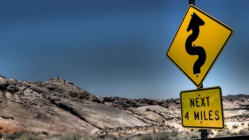 Road sign at mountains against blue sky