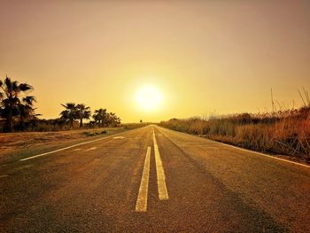 Surface level of road against sky during sunset