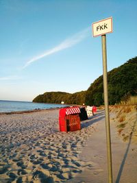 Road sign on beach against sky