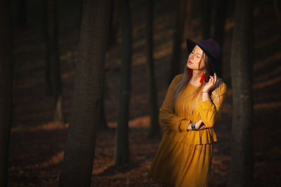 Young woman looking away in forest during winter