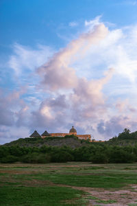 Built structure on landscape against cloudy sky