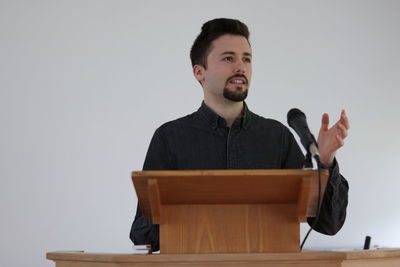 Portrait of young man looking away against white background