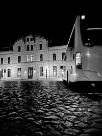 Illuminated building by street against sky at night