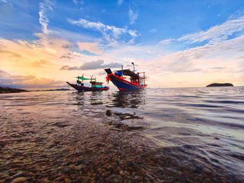 Boat in sea against sky during sunset