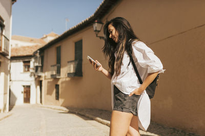 Young woman using phone while standing on street