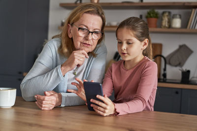 Granddaughter teaching using smart phone to grandma