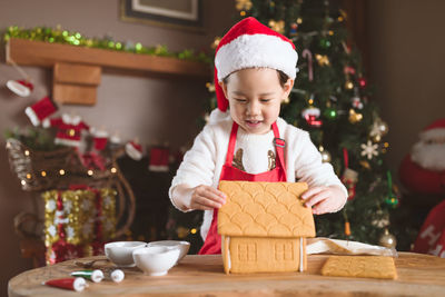 Young girl making gingerbread house at home