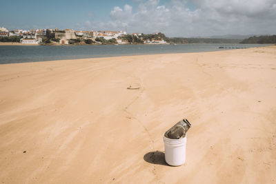 Containers on sand at beach against sky