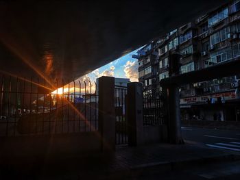 Illuminated street amidst buildings against sky at night