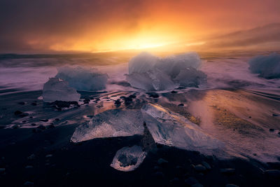 Frozen sea against sky during sunset