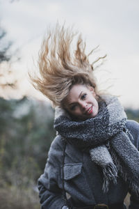 Portrait of young woman standing against trees