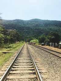 Railroad tracks by mountain against sky