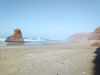 Scenic view of beach against clear blue sky