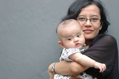 Close-up of cute girl sitting against wall