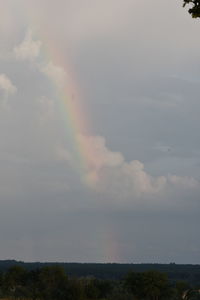 Low angle view of rainbow over landscape against sky