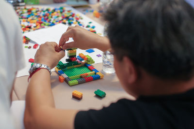 Rear view of man playing with blocks on table