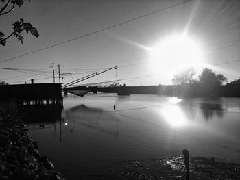 Silhouette bridge over water against sky