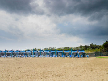 Scenic view of beach chairs against cloudy sky