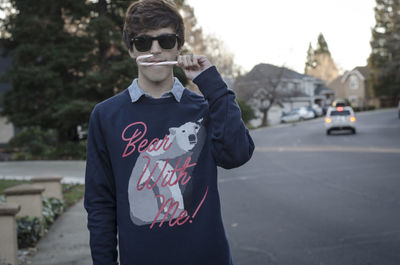 Portrait of young woman wearing sunglasses standing on street