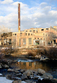 Buildings by river against sky