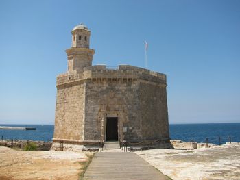 View of castle by sea against clear blue sky