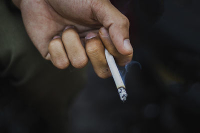 Cropped hand of person holding cigarette