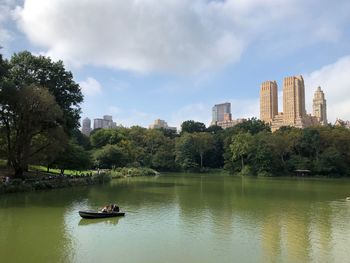 Boats in river amidst buildings against sky