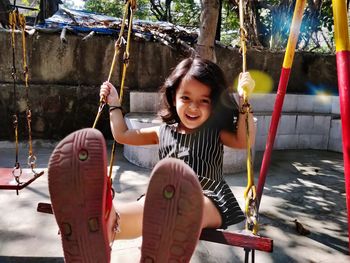 Portrait of smiling girl on swing in playground