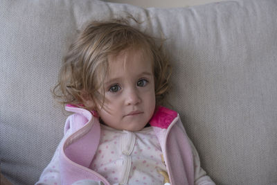 Little girl looking at the camera, on the couch in her living room.