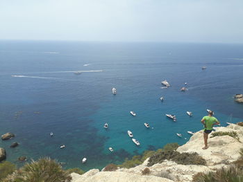 High angle view of man standing on rock against sea