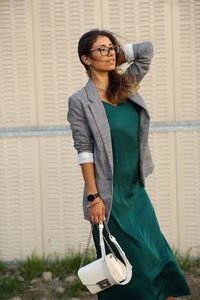 Woman looking away while standing on land against wall