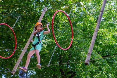 Adventure climbing high wire park - people on course in mountain helmet and safety equipment