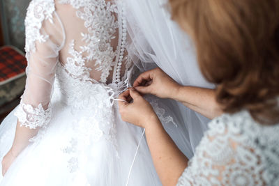 Midsection of bride holding wedding dress