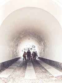 Rear view of people walking in tunnel