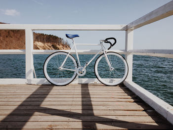 Bicycle parked on pier by sea