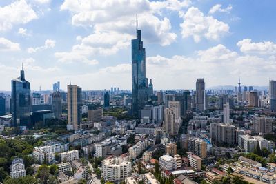 Aerial view of buildings in city against cloudy sky