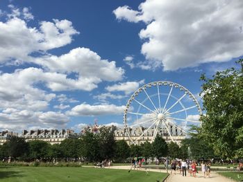 People walking on footpath in park roue de paris against sky in city