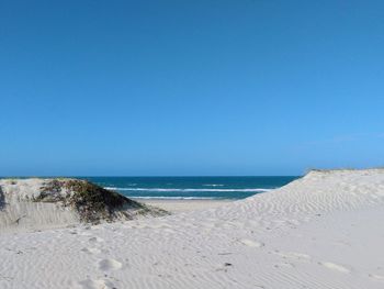 Scenic view of beach against clear blue sky