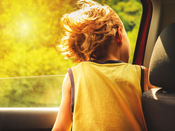 Rear view of boy standing on car