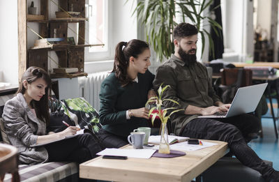 Business people working while sitting by table