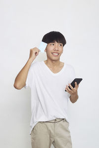 Full length of man holding mobile phone against white background