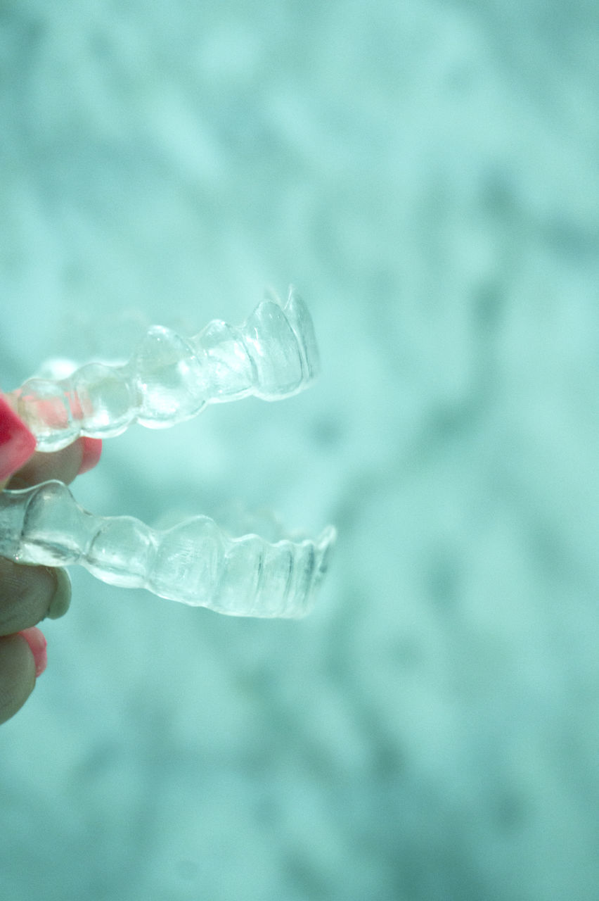 CLOSE-UP OF HAND HOLDING WATER IN BLURRED BACKGROUND